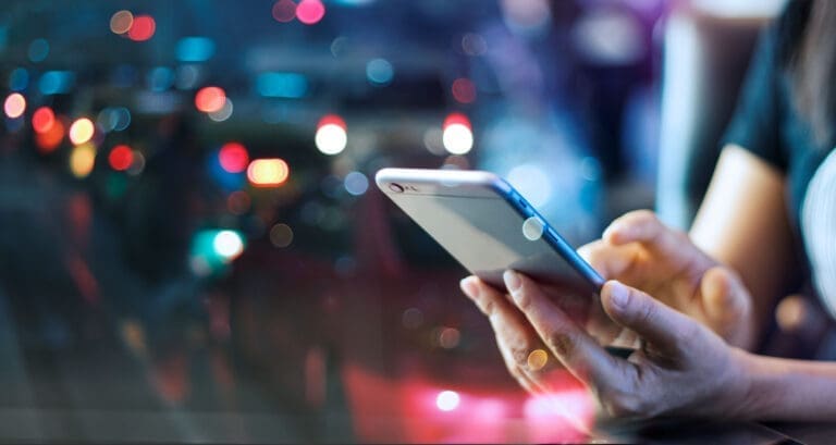 Woman using mobile smart phone in the night light colorful backg