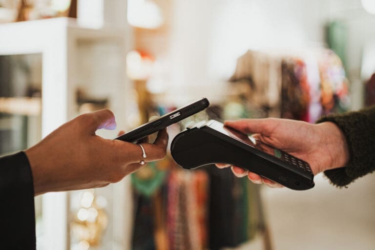 Close up shot of young woman paying contactless on a POS in a sh