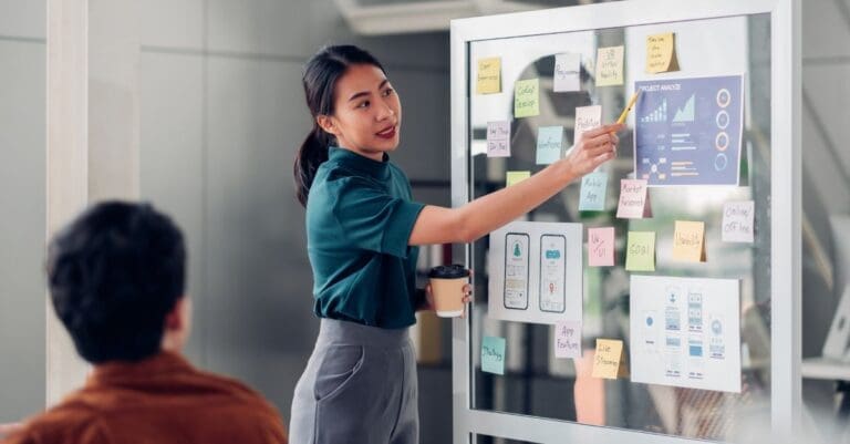 ux developer and ui designer presenting mobile app interface design on whiteboard in meeting at modern office