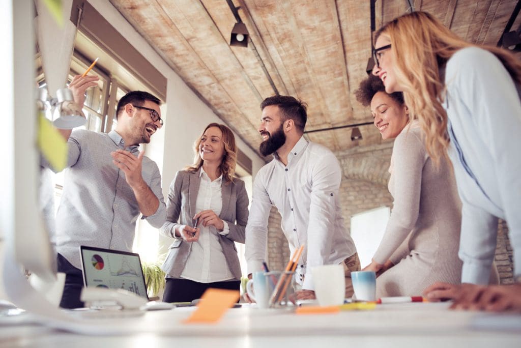 Team of employees in office surrounding table to discuss strategy